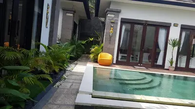 a house with a swimming pool in front of a house at Kubu Nesa in Jimbaran