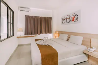 a white bedroom with a bed and a desk at The Salak Style Hotel in Denpasar