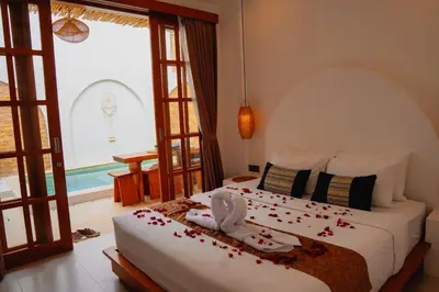 a bedroom with a bed with rose petals on it at La Rylin Villa in Kuta