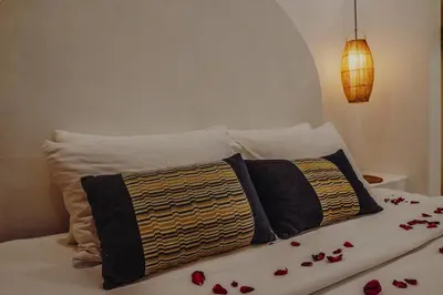 a bed with two pillows and flowers on it at La Rylin Villa in Kuta