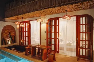 a dining room with a table and some windows at La Rylin Villa in Kuta