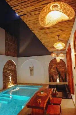 a large swimming pool in a room with a table and chairs at La Rylin Villa in Kuta