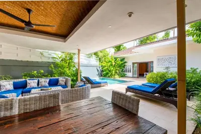 an outdoor patio with a wooden table and chairs at Omkara 2 BR Deluxe Private Pool Villa ZN253 in Seminyak