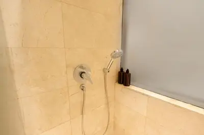 a shower with a shower head in a bathroom at Kuta Angel Hotel in Kuta