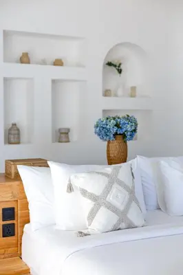 a white bed with white pillows and a vase of blue flowers at Villa Harper by BaliSuperHost in Canggu