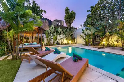 a pool with chaise lounge chairs and a swimming pool at Villa Jasmin Seminyak in Seminyak