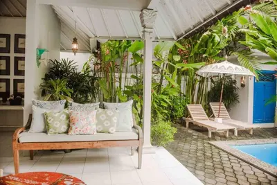 a porch with a bench with pillows next to a pool at 2 BedRoom Villa Hideaways Seminyak in Seminyak