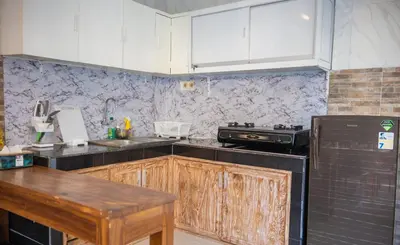 a kitchen with white cabinets and a black refrigerator at Lily Villa in Seminyak