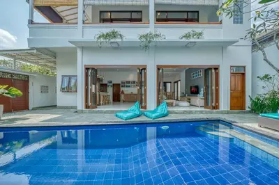 a villa with a swimming pool in front of a house at Villa Ima in Canggu