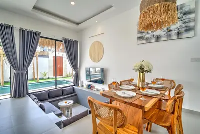 a dining room with a table and a couch at Villa Esha III in Seminyak