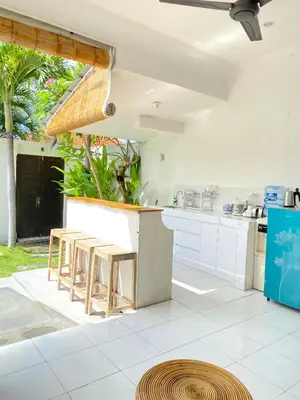an open kitchen with white counters and stools at Villa Music in Seminyak
