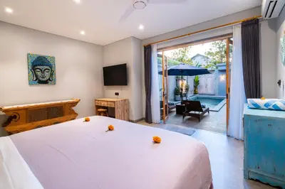 a bedroom with a large white bed and a patio at Villa Indah in Legian