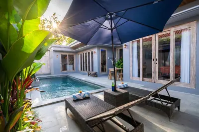 a house with a pool and an umbrella at Villa Indah in Legian