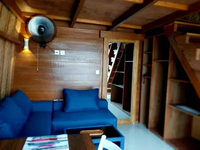 a living room with a blue couch and a fan at Thula Thula Bali Villas in Kerobokan