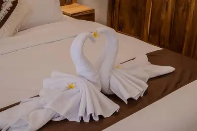 two white swans are sitting on a bed at Villa Cakka Seminyak in Seminyak