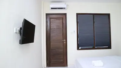 a room with a door and a television and a window at Puri Beach Inn - Poppies 2 in Legian