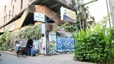 a man walking down a street next to a building with graffiti at Puri Beach Inn - Poppies 2 in Legian
