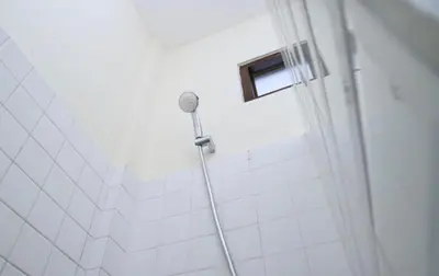 a shower with a shower head in a bathroom at Puri Beach Inn - Poppies 2 in Legian