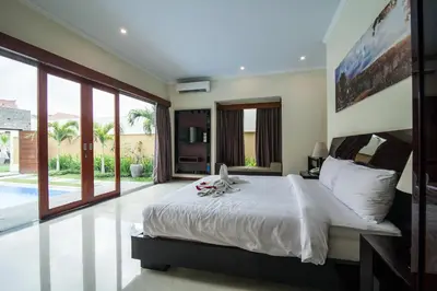 a bedroom with a large white bed and large windows at 1-BR Private Pool Villa Seminyak Kunti St in Seminyak