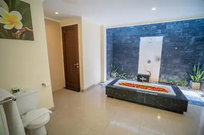 a bathroom with a toilet and a bathtub with flowers in it at 1-BR Private Pool Villa Seminyak Kunti St in Seminyak