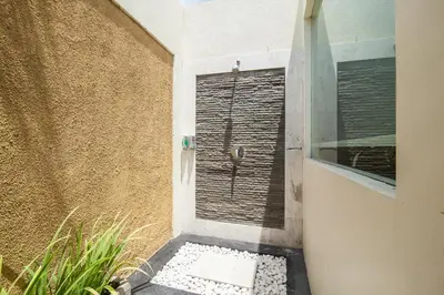 a bathroom with a walk in shower next to a wall at 1-BR Private Pool Villa Seminyak Kunti St in Seminyak