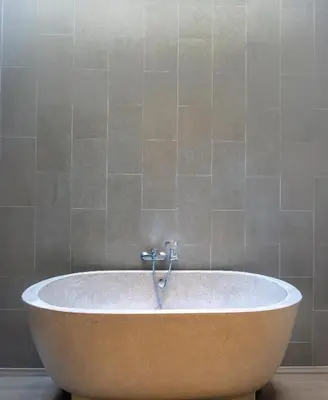 a bath tub in a bathroom with a tile wall at Villa Gregana by Pertama Management in Seminyak