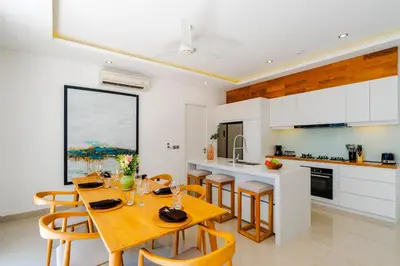 a kitchen and dining room with a wooden table and chairs at Villa Gregana by Pertama Management in Seminyak