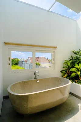 a large tub in a bathroom with a window at Villa Gregana by Pertama Management in Seminyak