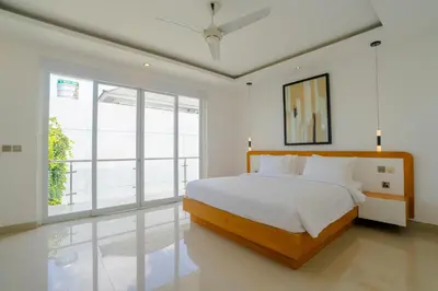 a white bedroom with a bed and a large window at Villa Gregana by Pertama Management in Seminyak