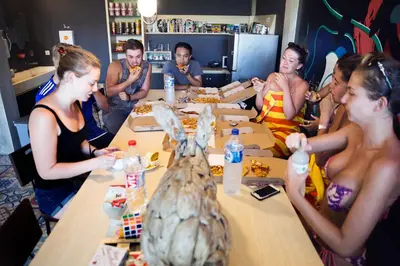 a group of people sitting around a table eating food at M Boutique Hostel in Seminyak
