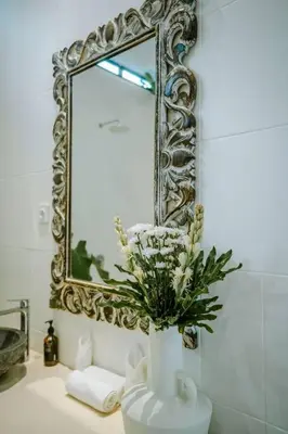 a bathroom sink with a mirror and a vase with flowers at Villa Kamboja 1 Seminyak in Seminyak