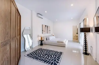 a white room with a bed and a black and white rug at Villa Kamboja 1 Seminyak in Seminyak