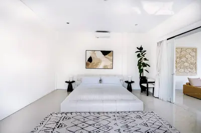 a white bedroom with a bed and a couch at Villa Kamboja 1 Seminyak in Seminyak