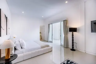 a white bedroom with a white bed and a window at Villa Kamboja 1 Seminyak in Seminyak