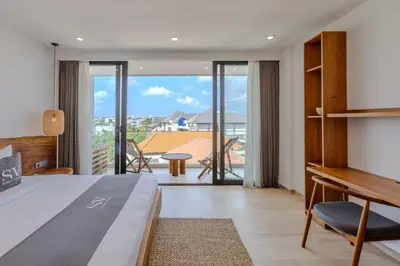 a bedroom with a bed and a view of a balcony at Sunny Aparts 2 in Canggu