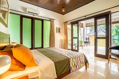 a bedroom with a bed in a room with large windows at Villa Amaro Seminyak in Seminyak