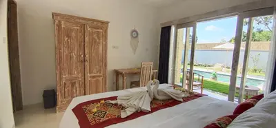 a bedroom with a bed and a large sliding glass door at The Lebak Sari Guesthouse in Umalas