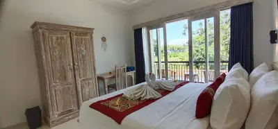 a bedroom with a large bed with a large window at The Lebak Sari Guesthouse in Umalas