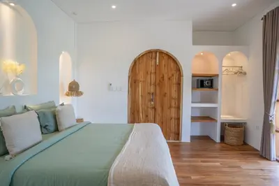 a bedroom with a large bed and a wooden door at Villa Bohemian Seminyak in Seminyak