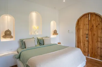 a bedroom with a large bed and a wooden door at Villa Bohemian Seminyak in Seminyak