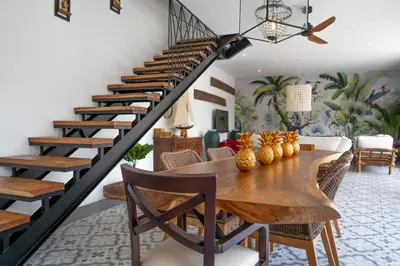 a dining room with a table and a spiral staircase at Villa Rhapsody Seminyak in Seminyak