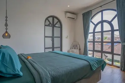 a bedroom with a bed and two large windows at Villa Rhapsody Seminyak in Seminyak