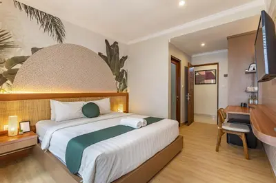 a bedroom with a large bed with a desk and a piano at Cove Vin Stay in Sanur