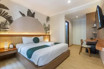 a bedroom with a bed and a desk and a television at Cove Vin Stay in Sanur