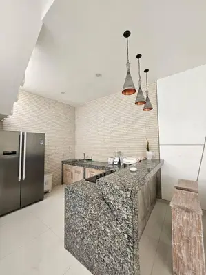 a kitchen with a granite counter top and a refrigerator at Nikaya Villa - 3 Bedrooms Near Seminyak in Legian