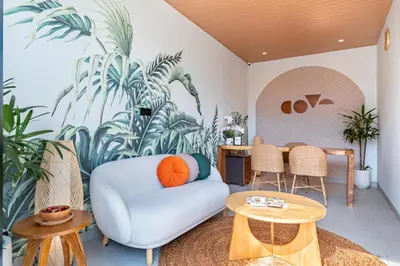 a living room with a blue couch and a palm mural at Cove Anantaha Loft & Villa in Seminyak