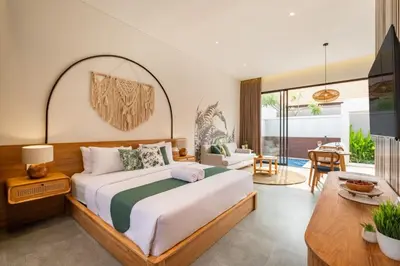a bedroom with a large bed and a living room at Cove Anantaha Loft & Villa in Seminyak
