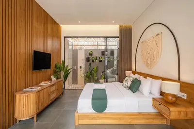 a bedroom with a large bed and a television at Cove Anantaha Loft & Villa in Seminyak