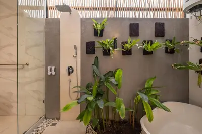 a bathroom with potted plants on a wall at Cove Anantaha Loft & Villa in Seminyak
