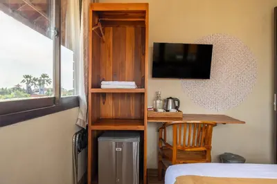 a room with a bed and a desk with a television at Cove Kavana in Canggu